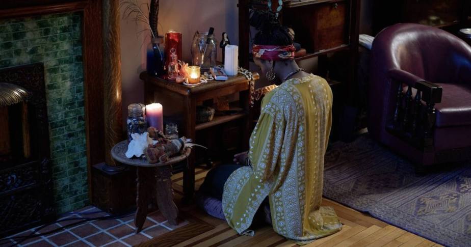 Une personne assise devant un autel maison, entourée de bougies, créant une ambiance chaleureuse et accueillante.