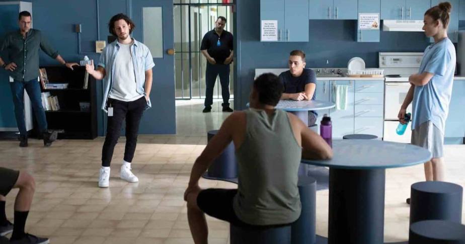 Des personnes sont réunies dans une pièce, entourées de tables et de chaises, participant à une conversation.